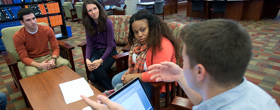 Dr. Jennifer Van Reet meeting with 3 students in the library