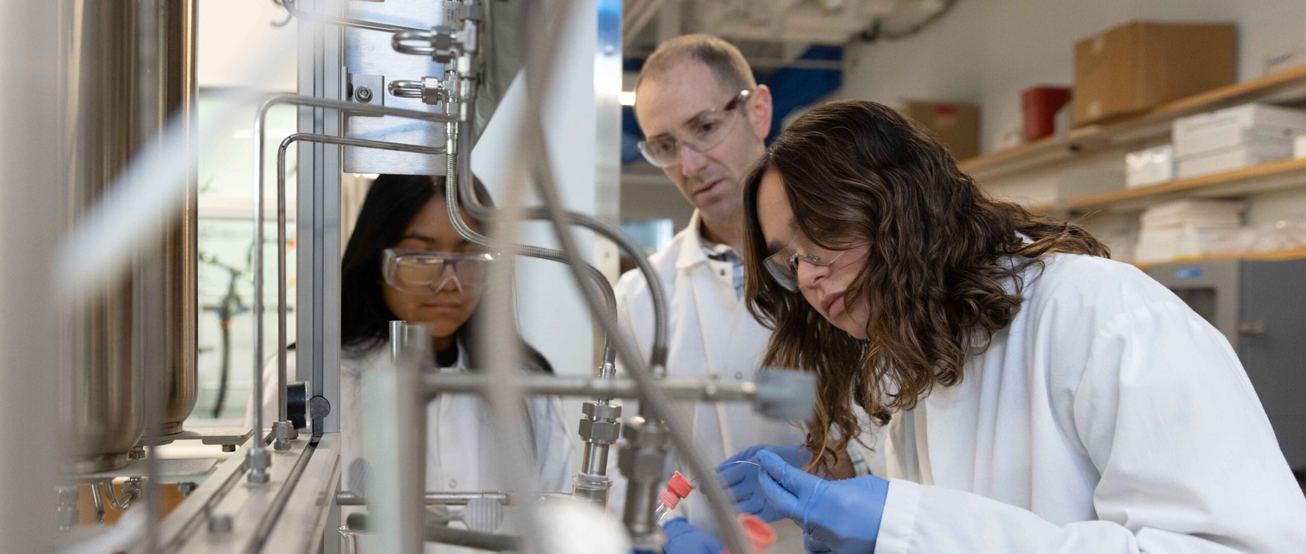 Two female students working with a professor in a Chemistry Lab