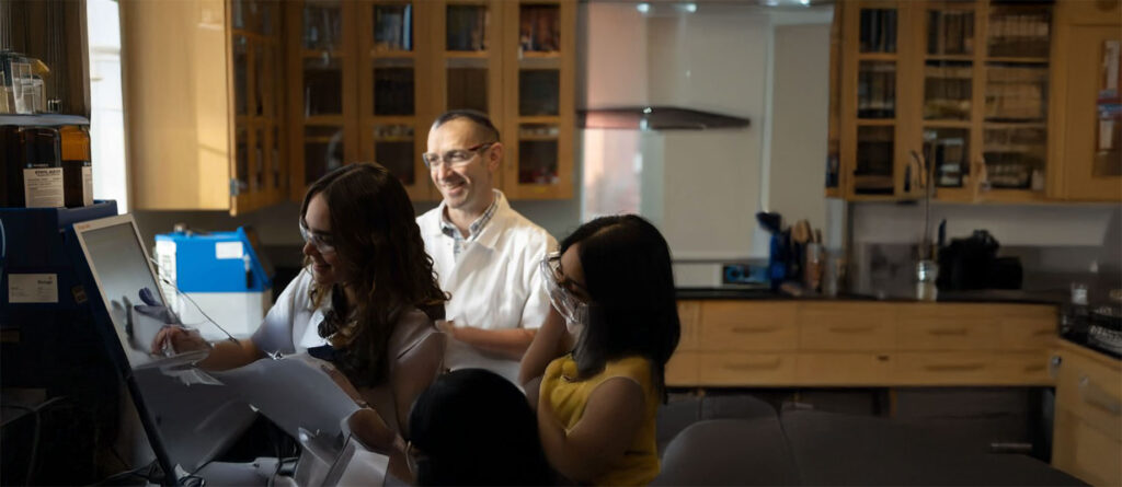 Dr. Seann Mulcahy working in a lab with two female students